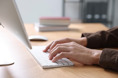 Photo of Man working on computer at wooden desk in office, closeup