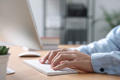 Photo of Man working on computer at wooden desk in office, closeup