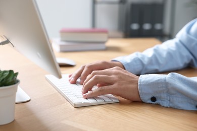 Photo of Man working on computer at wooden desk in office, closeup