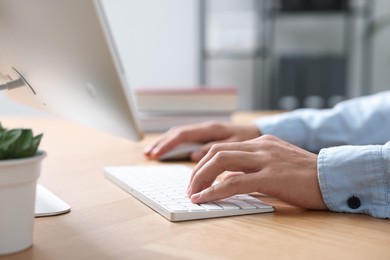 Photo of Man working on computer at wooden desk in office, closeup