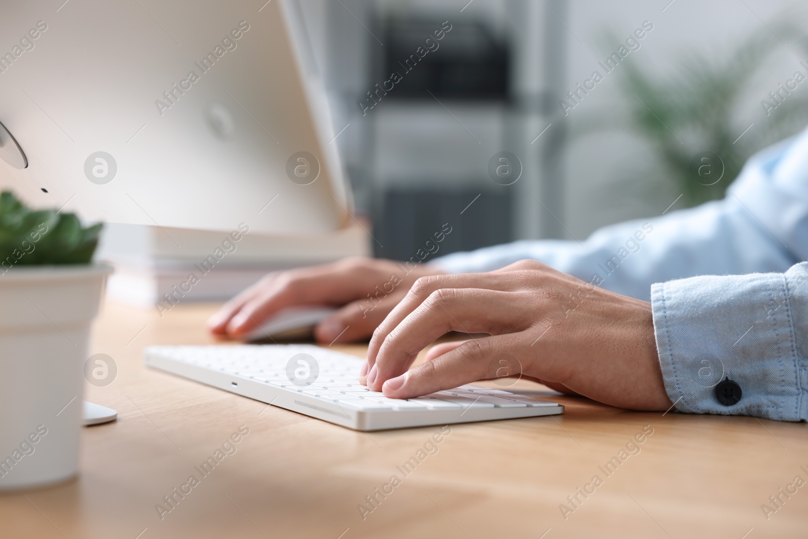 Photo of Man working on computer at wooden desk in office, closeup