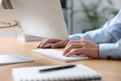 Photo of Man working on computer at wooden desk in office, closeup