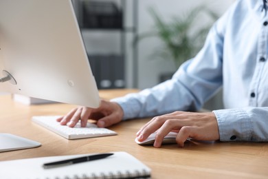 Photo of Man working on computer at wooden desk in office, closeup