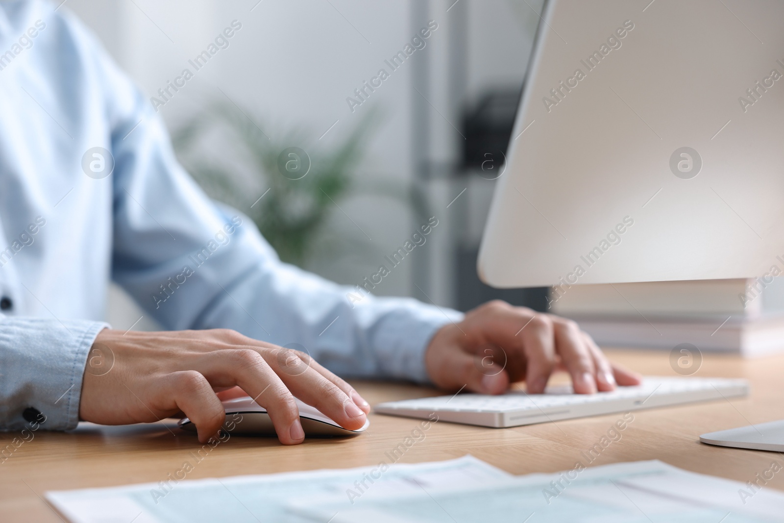 Photo of Man working on computer at wooden desk in office, closeup