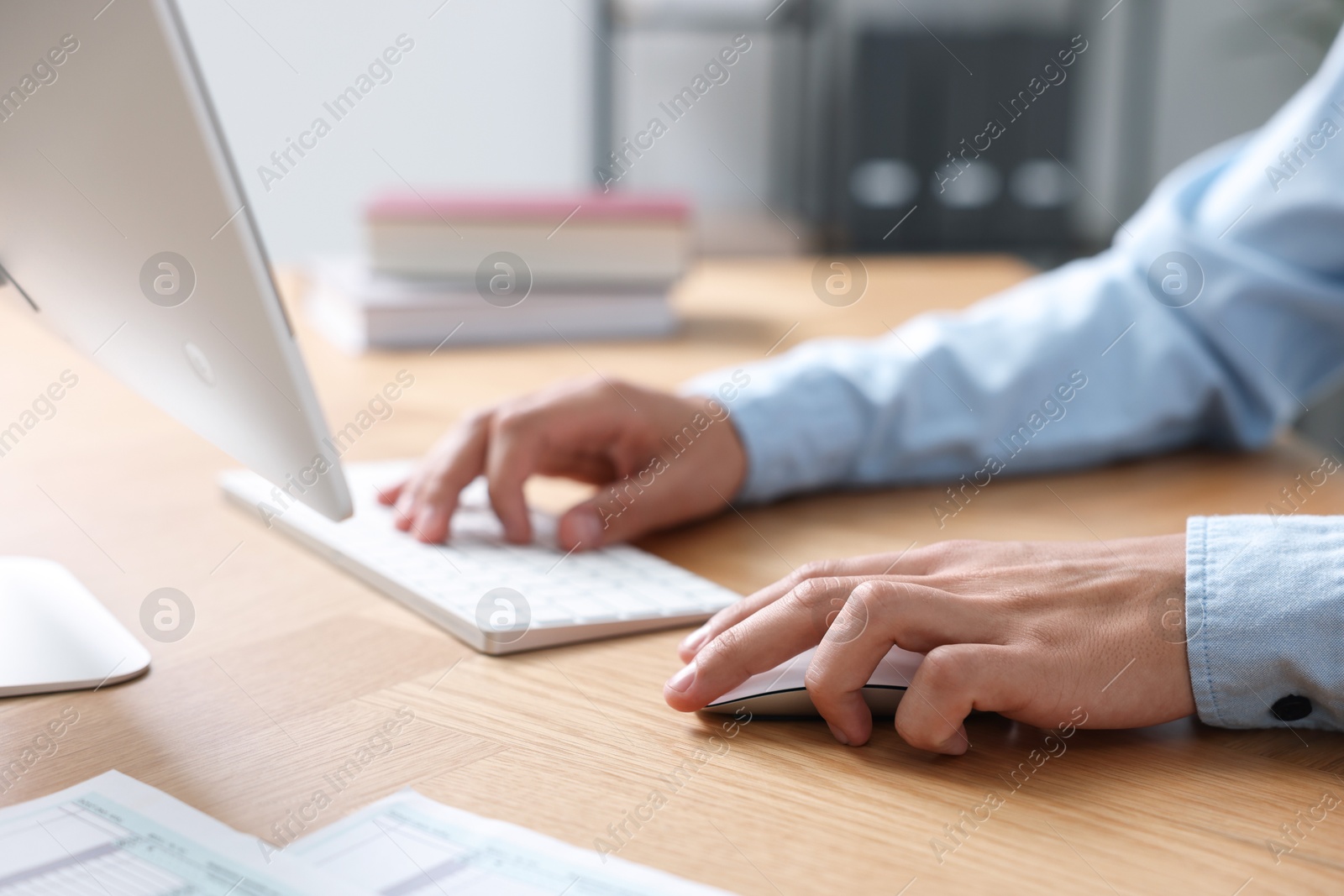 Photo of Man working on computer at wooden desk in office, closeup