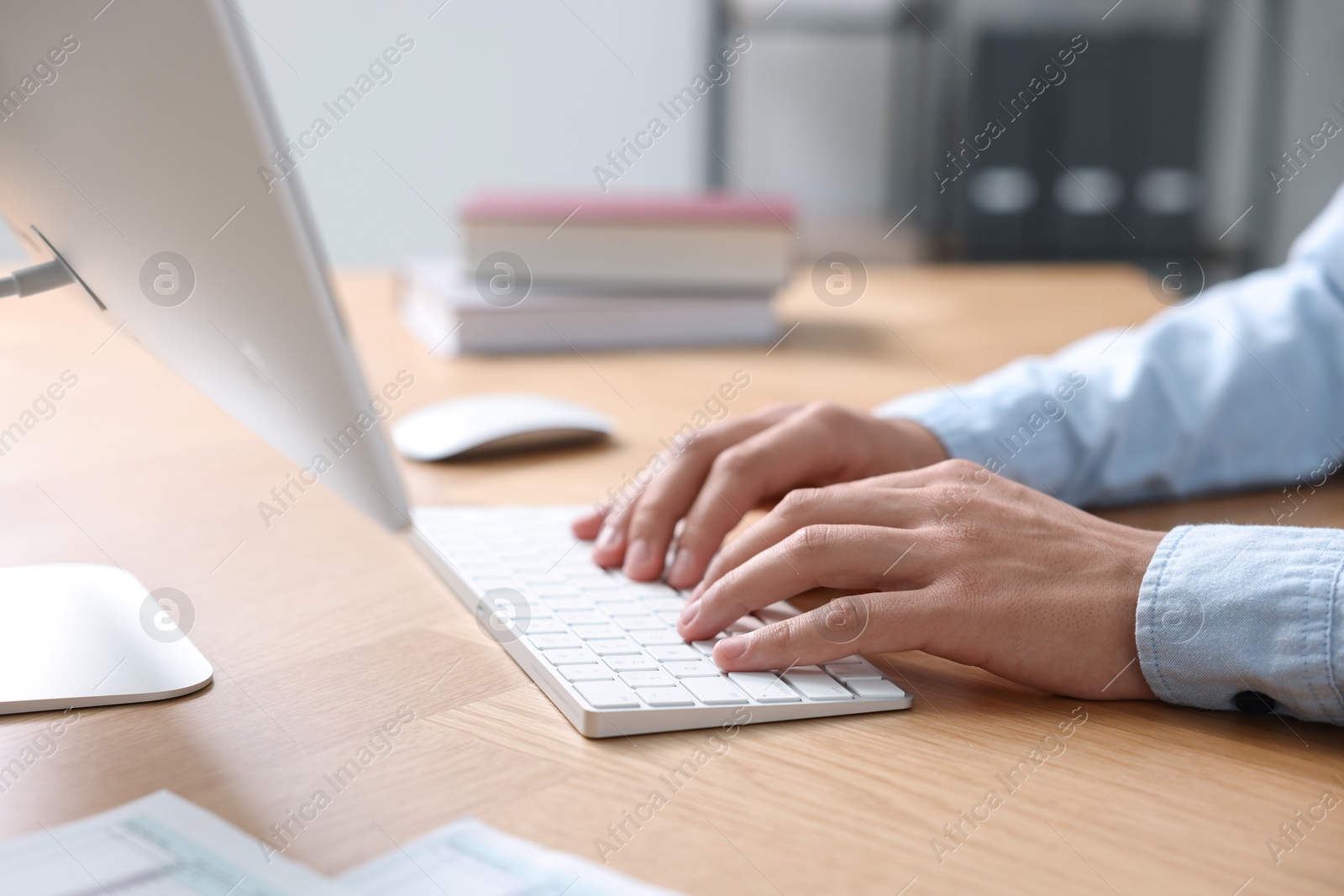 Photo of Man working on computer at wooden desk in office, closeup