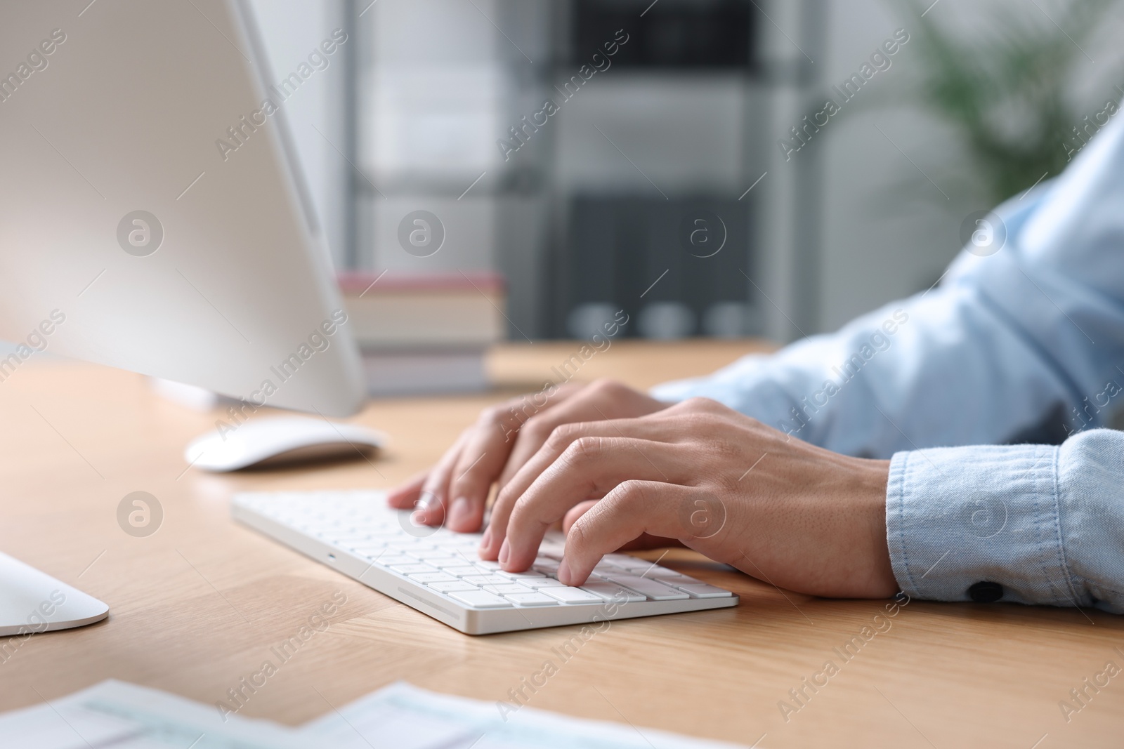 Photo of Man working on computer at wooden desk in office, closeup