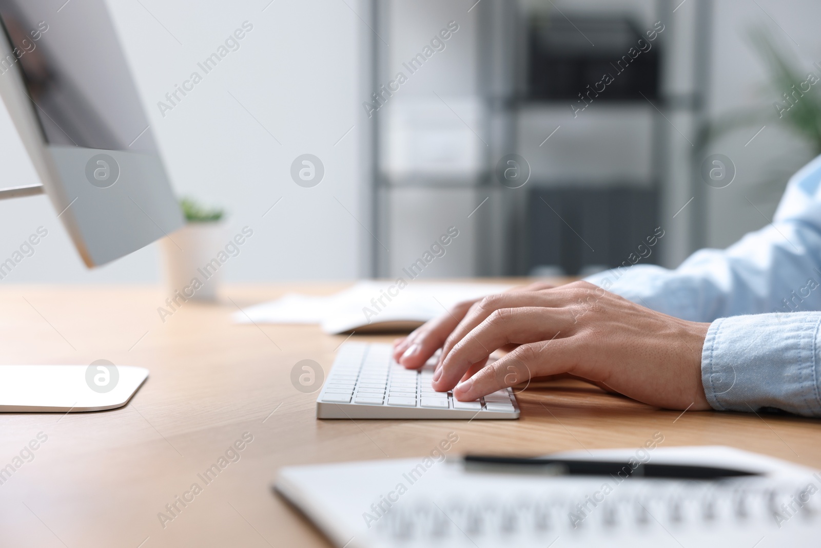 Photo of Man working on computer at wooden desk in office, closeup