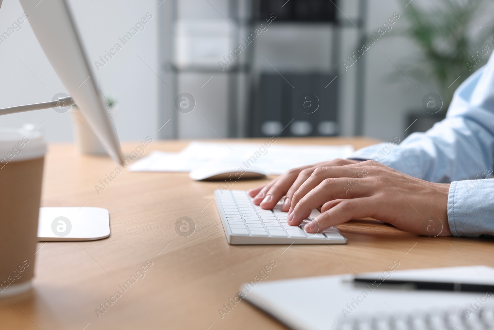 Photo of Man working on computer at wooden desk in office, closeup