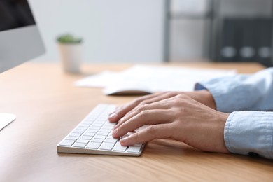 Photo of Man working on computer at wooden desk in office, closeup