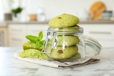 Photo of Delicious mint chocolate chip cookies in jar on white marble table, closeup