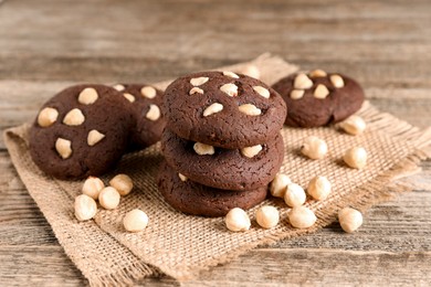 Photo of Tasty chocolate cookies with hazelnuts on wooden table, closeup