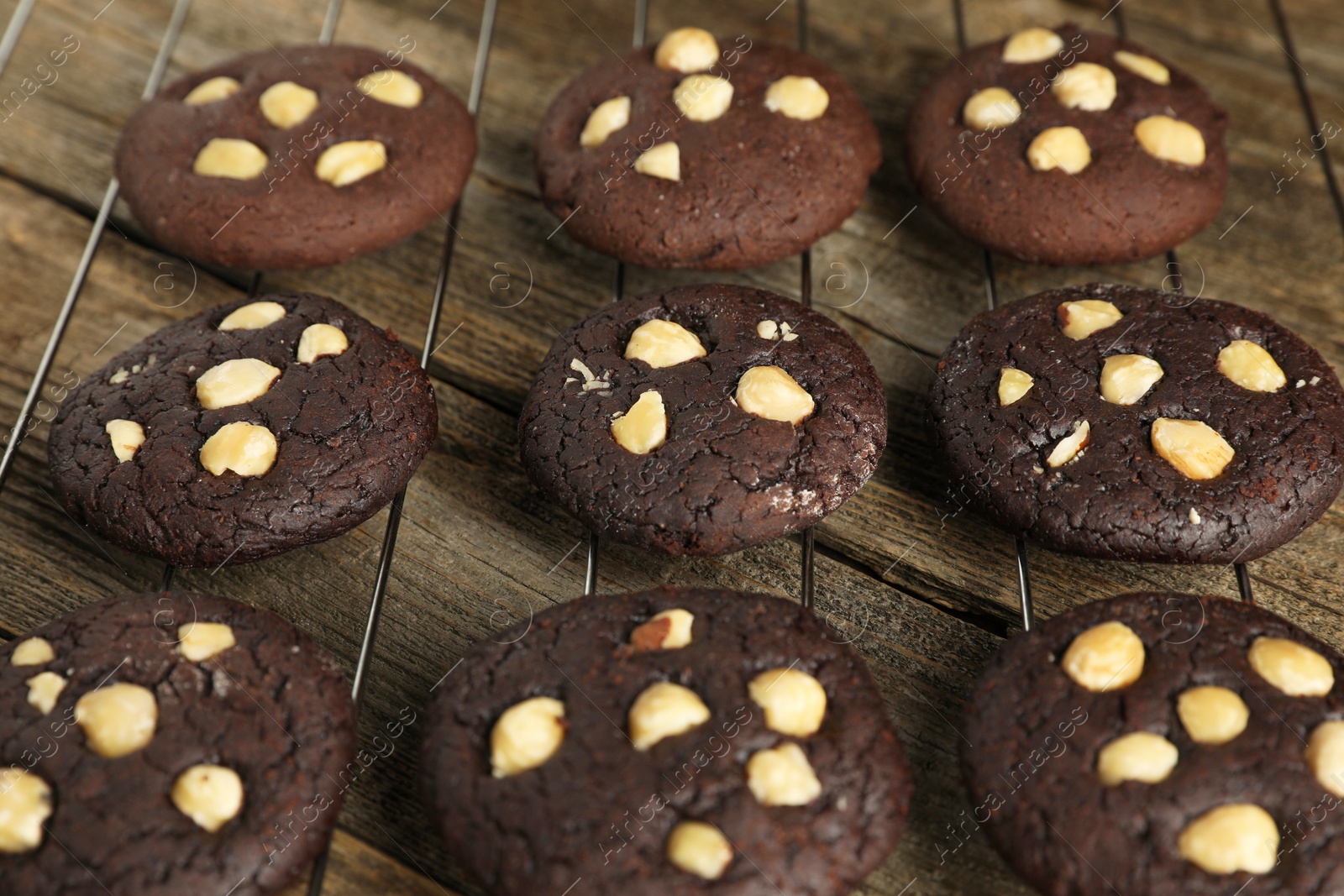 Photo of Tasty chocolate cookies with hazelnuts on wooden table, closeup