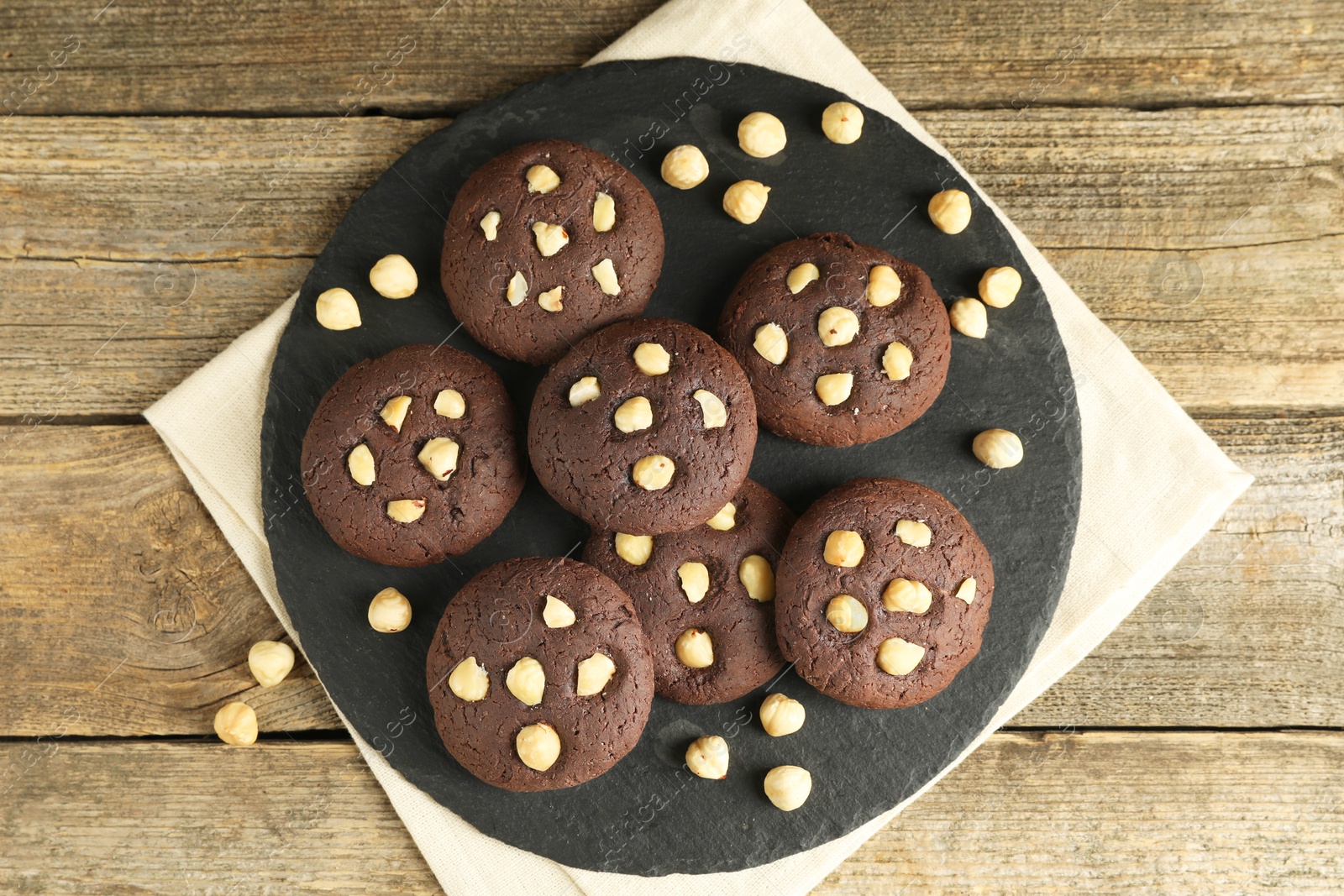 Photo of Tasty chocolate cookies with hazelnuts on wooden table, top view