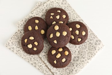 Photo of Tasty chocolate cookies with hazelnuts on white table, top view