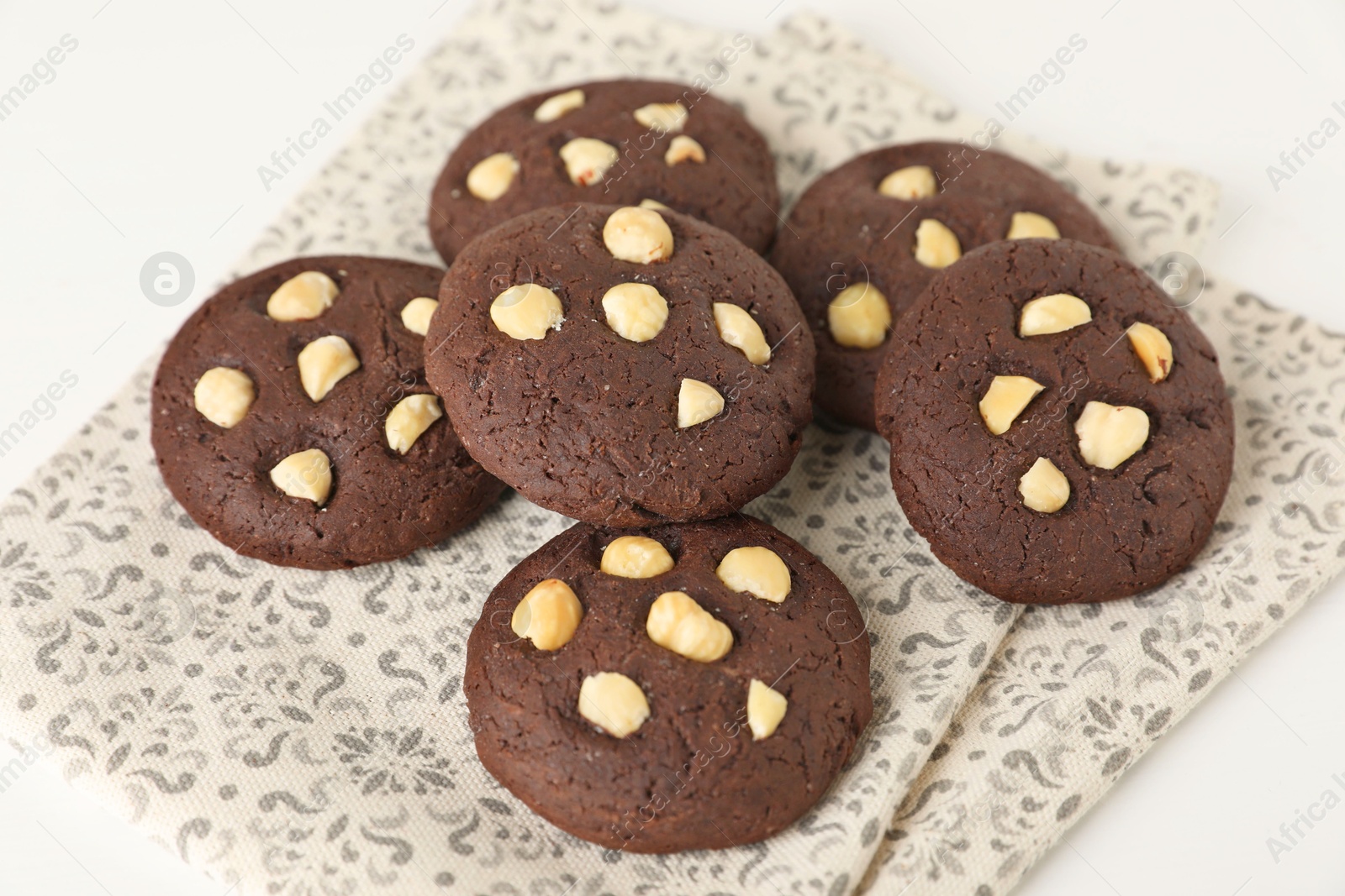 Photo of Tasty chocolate cookies with hazelnuts on white table, closeup