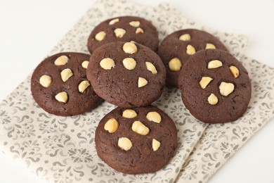 Photo of Tasty chocolate cookies with hazelnuts on white table, closeup