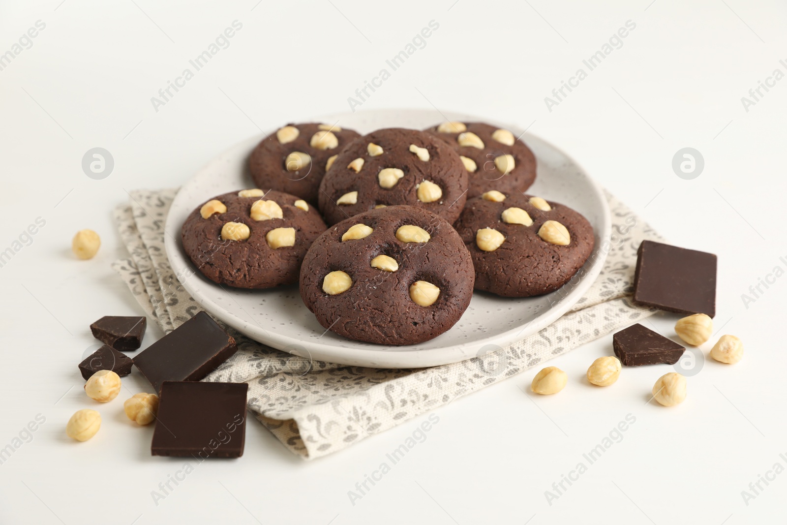 Photo of Tasty chocolate cookies with hazelnuts on white table, closeup