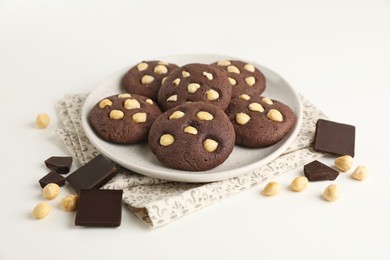 Photo of Tasty chocolate cookies with hazelnuts on white table, closeup