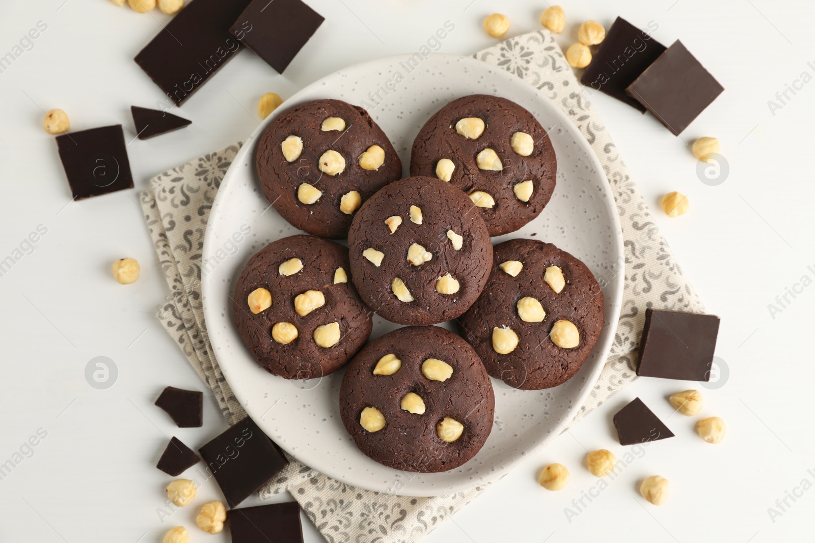 Photo of Tasty chocolate cookies with hazelnuts on white table, flat lay