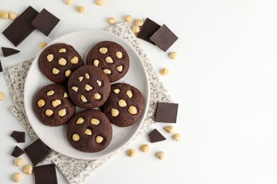 Photo of Tasty chocolate cookies with hazelnuts on white table, flat lay. Space for text