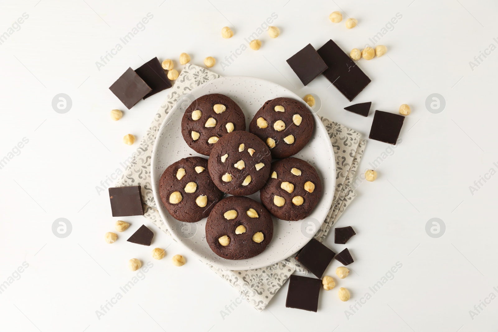 Photo of Tasty chocolate cookies with hazelnuts on white table, flat lay