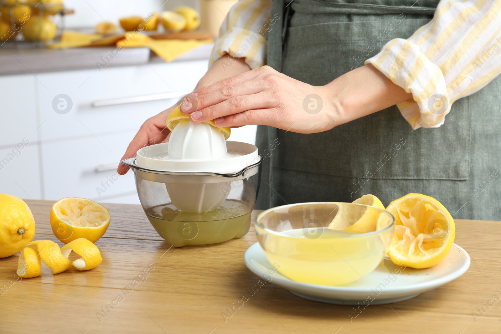 Photo of Woman with lemon using juicer at wooden table, closeup