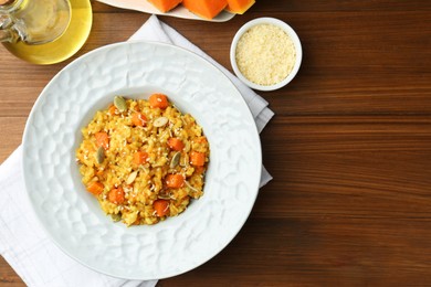 Photo of Delicious pumpkin risotto on wooden table, flat lay