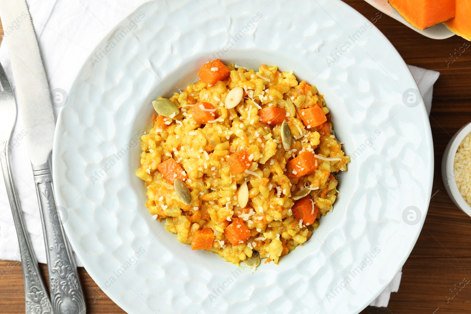 Photo of Delicious pumpkin risotto served on wooden table, top view
