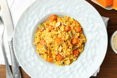 Photo of Delicious pumpkin risotto served on wooden table, top view
