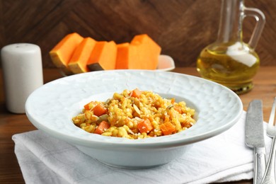 Photo of Delicious pumpkin risotto served on wooden table, closeup