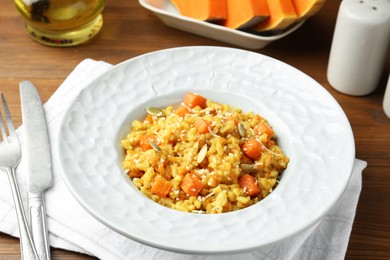 Photo of Delicious pumpkin risotto served on wooden table, closeup