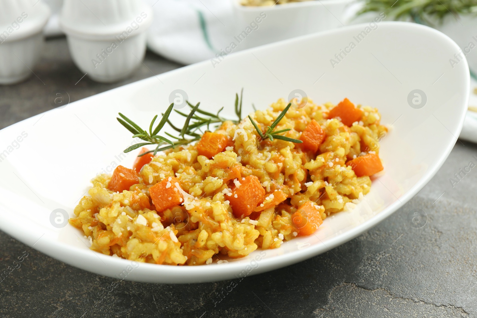 Photo of Delicious pumpkin risotto on grey table, closeup