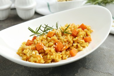 Photo of Delicious pumpkin risotto on grey table, closeup