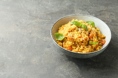 Photo of Delicious pumpkin risotto with basil on grey table. Space for text