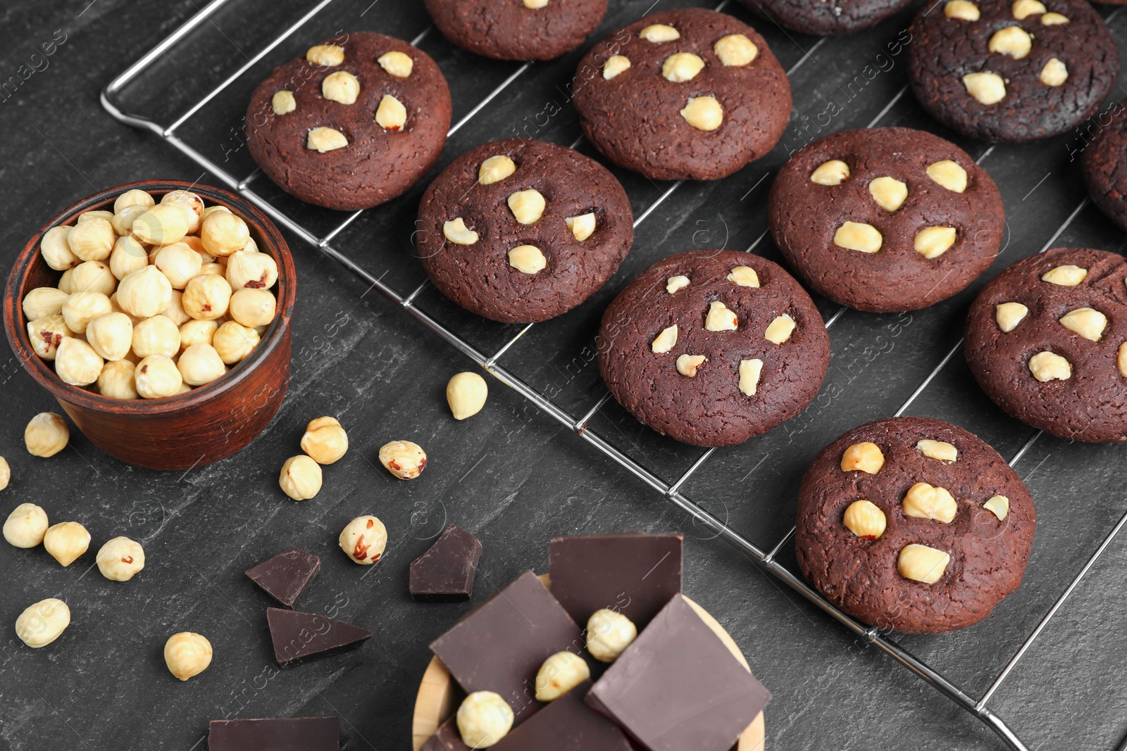 Photo of Tasty chocolate cookies with hazelnuts on black table, closeup