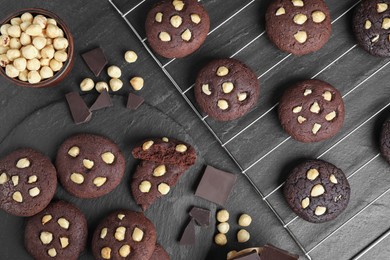 Photo of Tasty chocolate cookies with hazelnuts on black table, flat lay