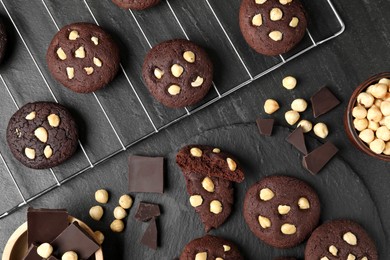 Photo of Tasty chocolate cookies with hazelnuts on black table, flat lay