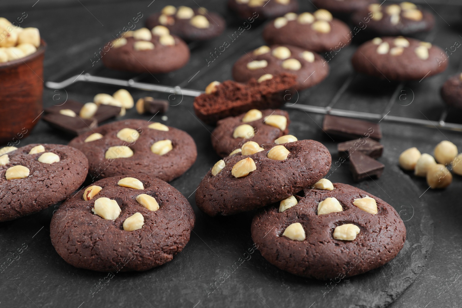 Photo of Tasty chocolate cookies with hazelnuts on black table, closeup