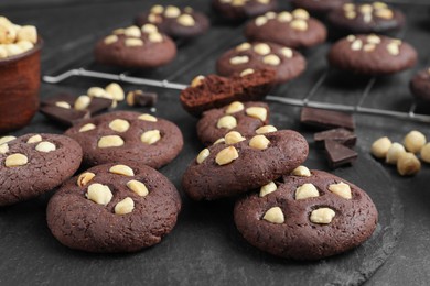 Photo of Tasty chocolate cookies with hazelnuts on black table, closeup