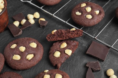 Photo of Tasty chocolate cookies with hazelnuts on black table, closeup