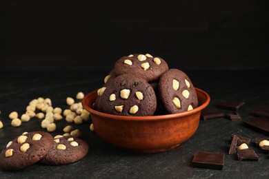 Photo of Tasty chocolate cookies with hazelnuts on black table