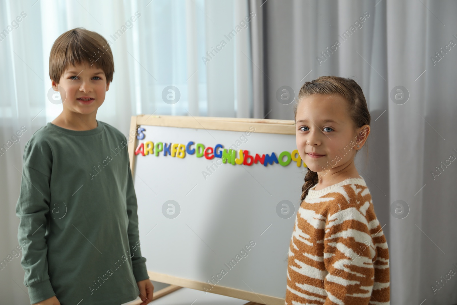 Photo of Little kids learning alphabet with magnetic letters indoors