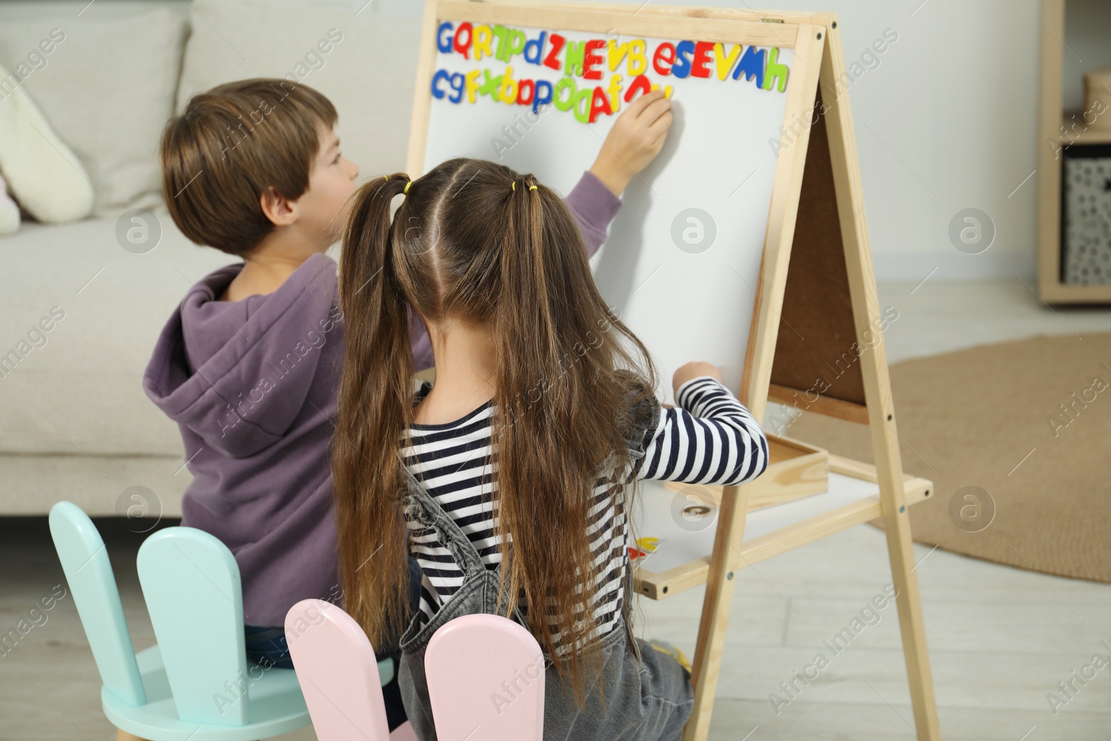 Photo of Little kids learning alphabet with magnetic letters indoors