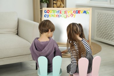 Photo of Little kids learning alphabet with magnetic letters indoors, back view