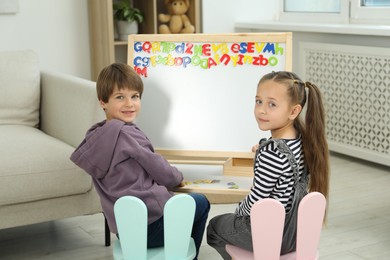 Photo of Little kids learning alphabet with magnetic letters indoors