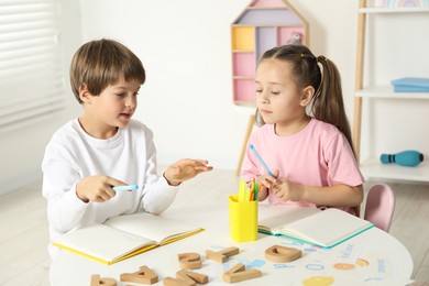 Photo of Little kids learning alphabet at white table indoors