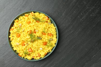 Photo of Delicious pumpkin risotto in bowl on black table, top view. Space for text