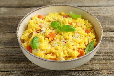 Photo of Delicious pumpkin risotto in bowl on wooden table, closeup