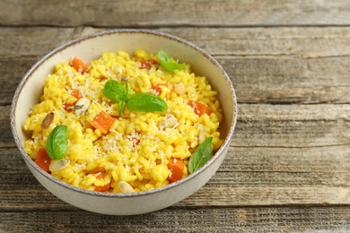 Photo of Delicious pumpkin risotto in bowl on wooden table, closeup. Space for text